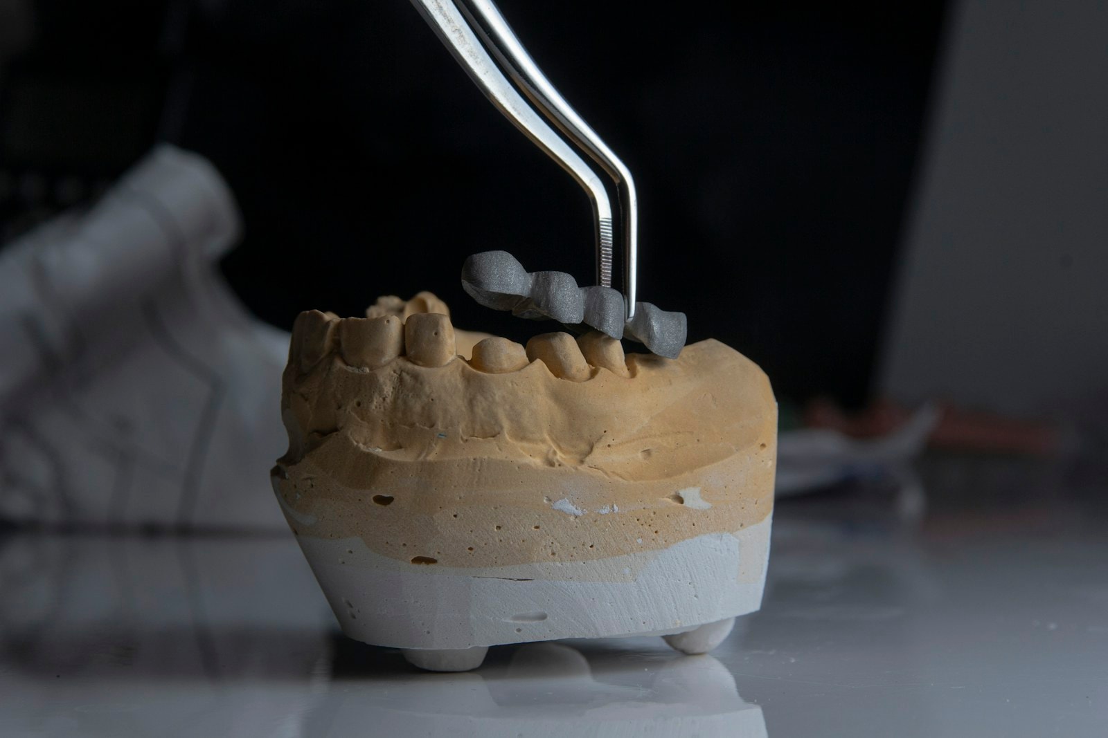 Coroană dentară poziționată cu penseta pe un model de laborator